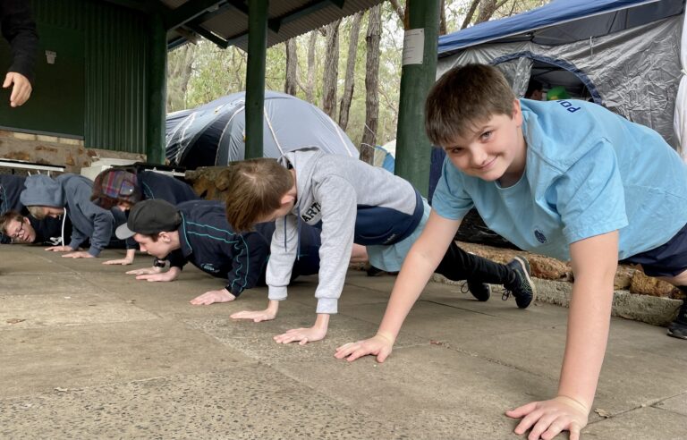 Students crawling under a low obstacle during a training activity