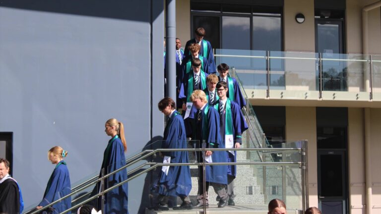 Year 12 graduates in their gowns walking down the stairs at the Valedictory and Graduation Assembly 2026