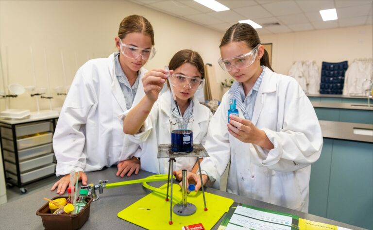 Secondary students in lab coats conducting a chemistry experiment